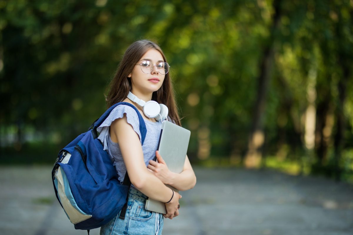 Jovem universitária carrega seus materiais pelo campus