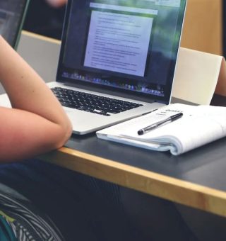 Jovem sentando em frente a um notebook conferindo os detalhes dos Vestibulares Online 2024