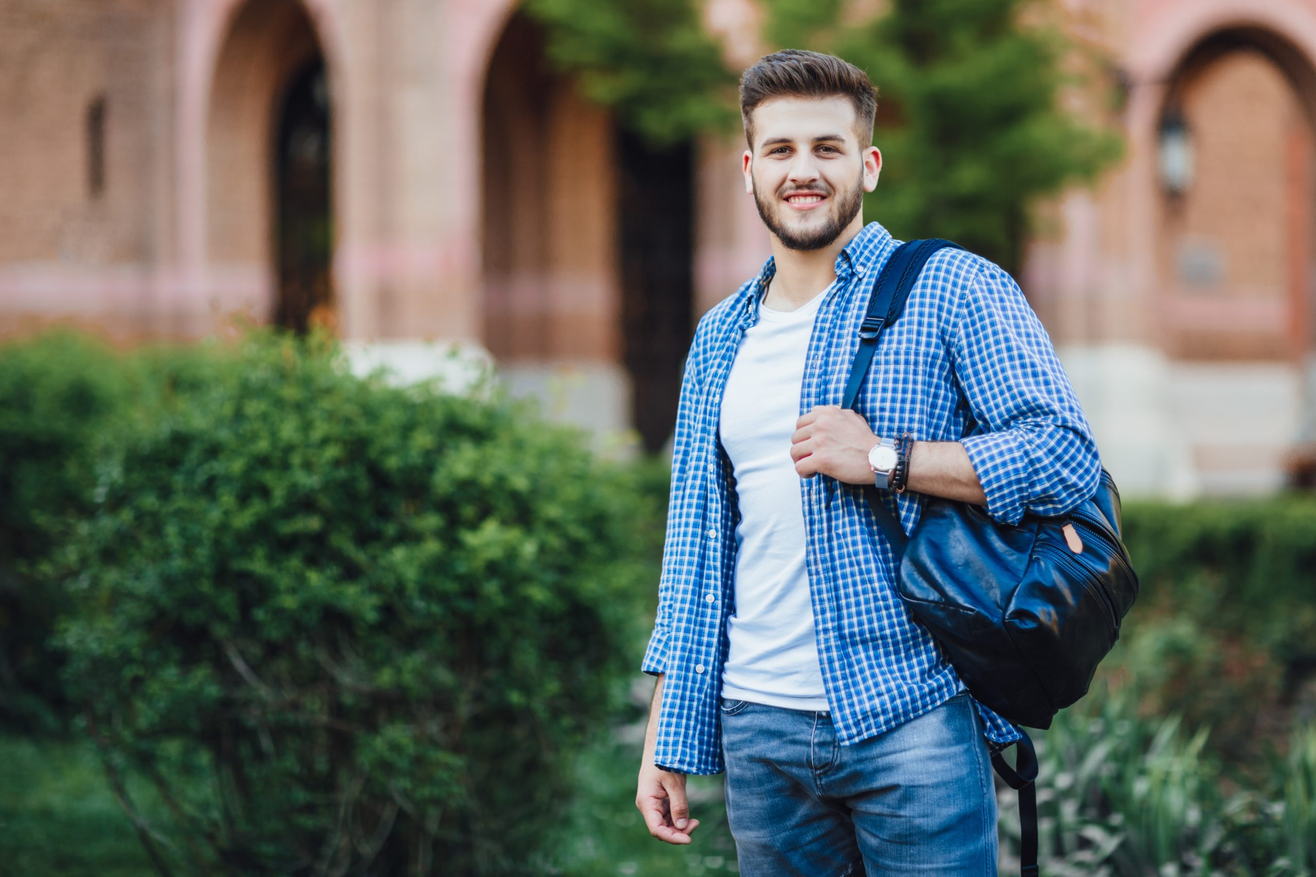 Estudante universitário posa com mochila nas costas no campus da universidade