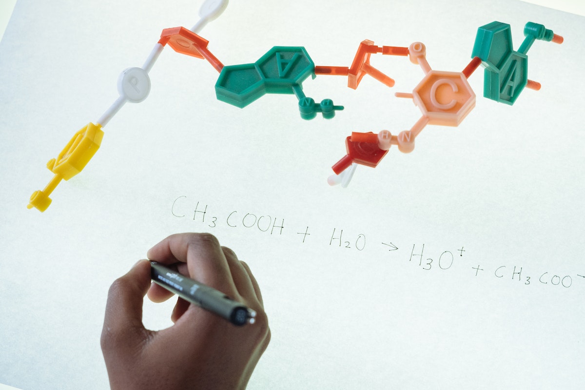 Imagem de uma mão escrevendo uma fórmula de biologia
