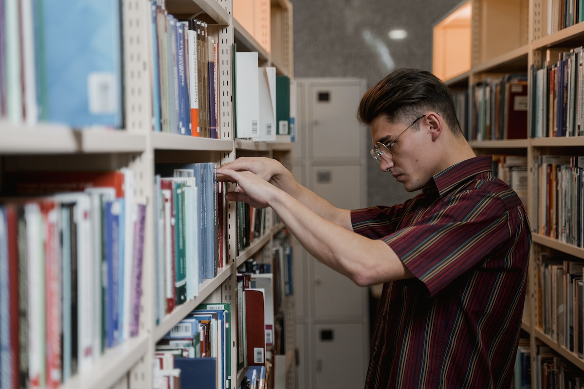 Um aluno está no corredor de uma biblioteca escolhendo um livro