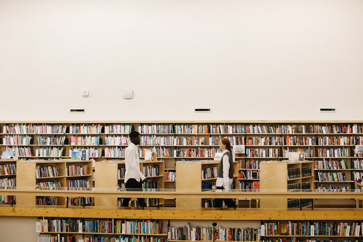 Uma grande biblioteca onde alguns alunos aparecem, buscando se preparar para o Vestibular Unibrasil 2024