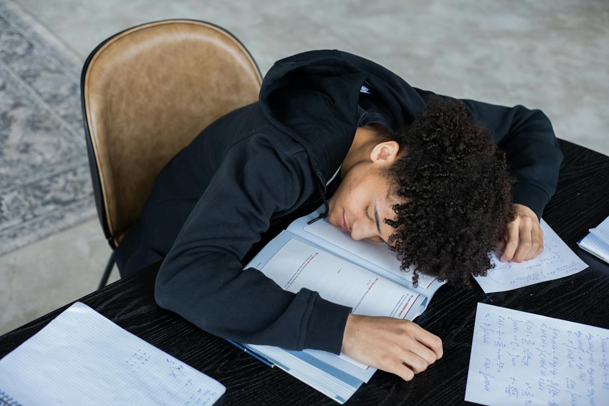 Um aluno dorme em cima do material escolar. Ele se prepara para o Vestibular Unisuam 2024