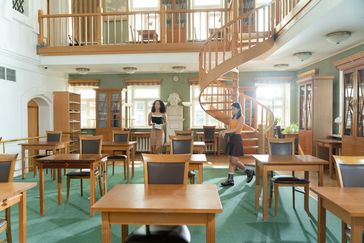 Imagem de uma sala de estudo com dois andares, uma aluno está na sala que é cheia de móveis de madeira