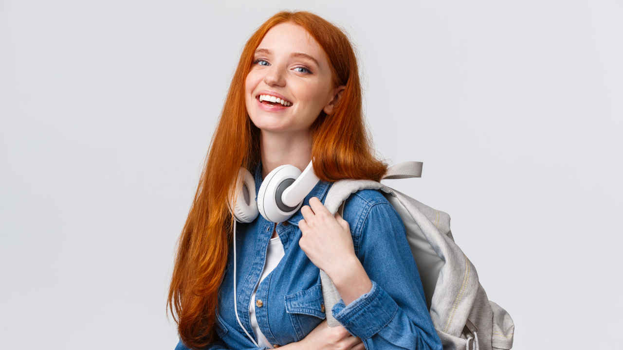 Garota ruiva sorrindo com mochila nas costas