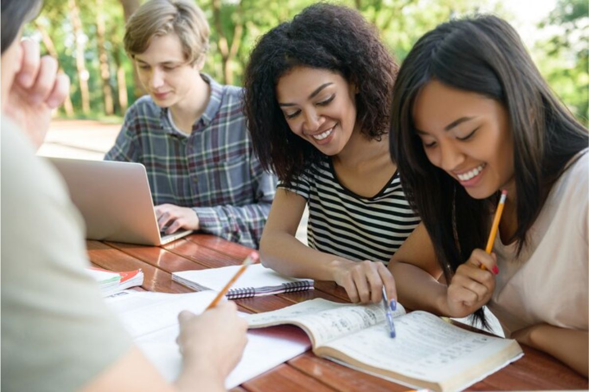 Um grupo de alunos sentado em uma mesa enquanto estudam. Um deles está no notebook e vê quando sai o Resultado da UFSC 2024