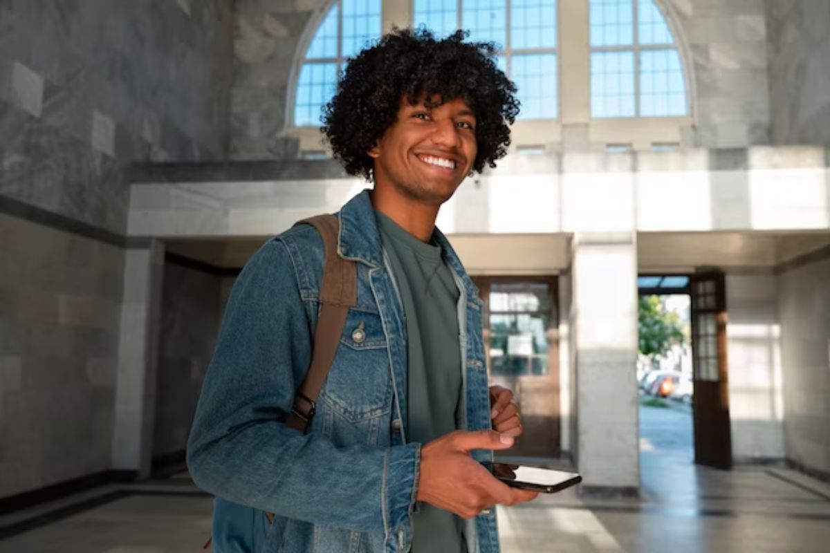 Um aluno está sorrindo dentro do salão principal da universidade